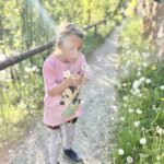 Kind pflückt Pusteblume beim Spaziergang